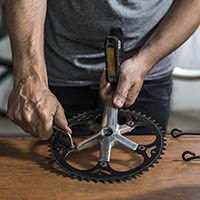a person fixing a part of a cycle that has the pedal attached to it